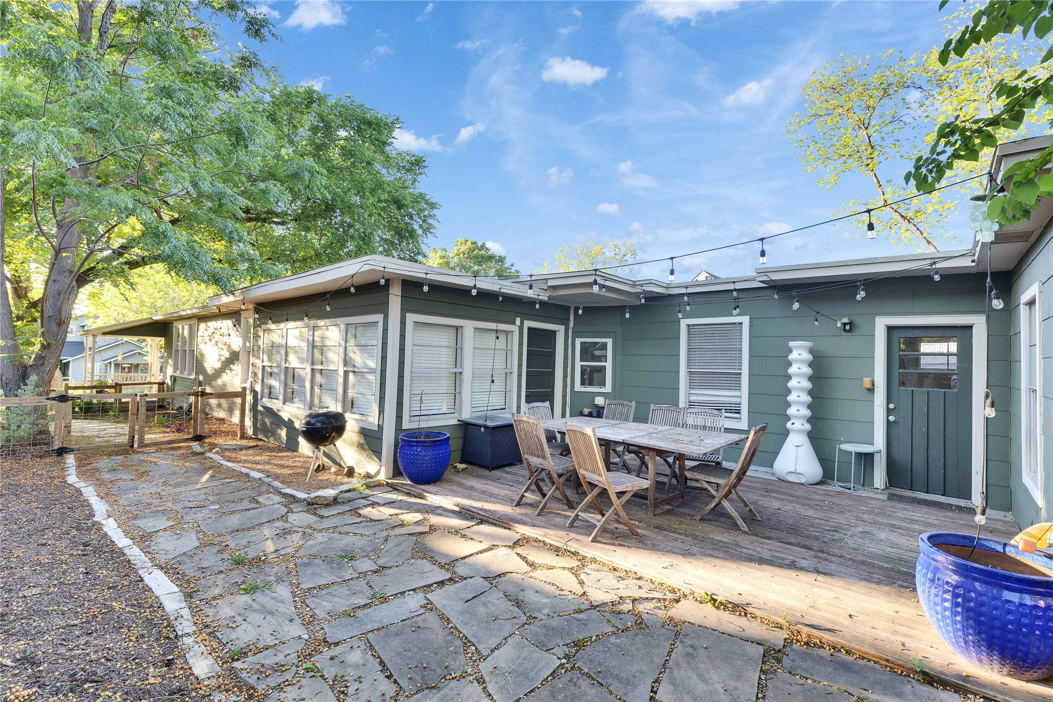 4607 Evans Avenue, Unit B Austin, TX 78751 - Photo 26 of 34 Expansive outdoor living area featuring a flagstone patio, wood deck, string lighting, and mature trees
