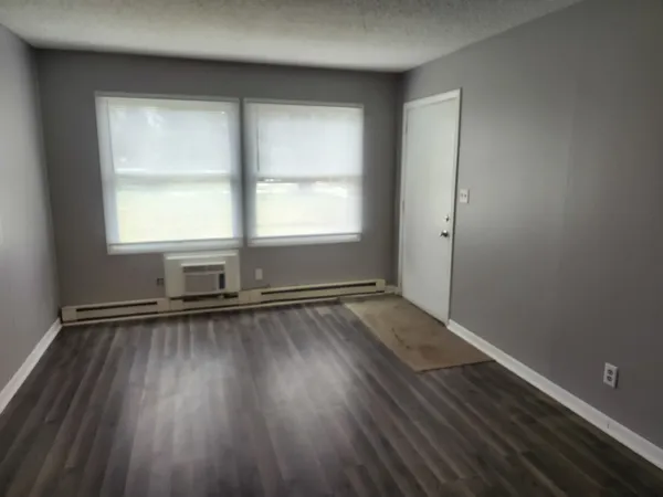 an empty room with wooden floor and windows