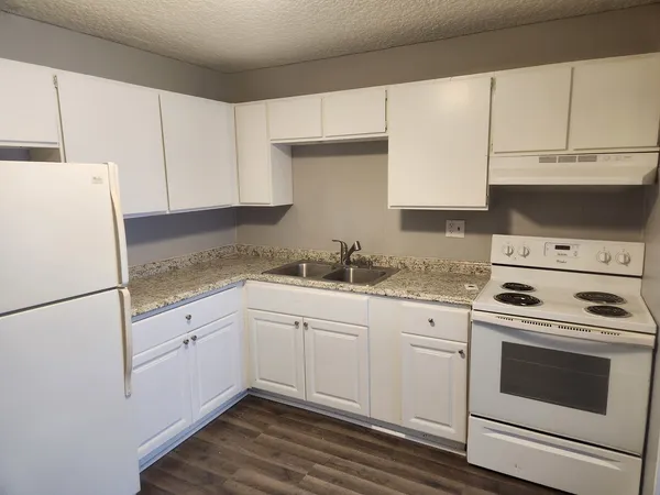 a kitchen with granite countertop white cabinets and white appliances