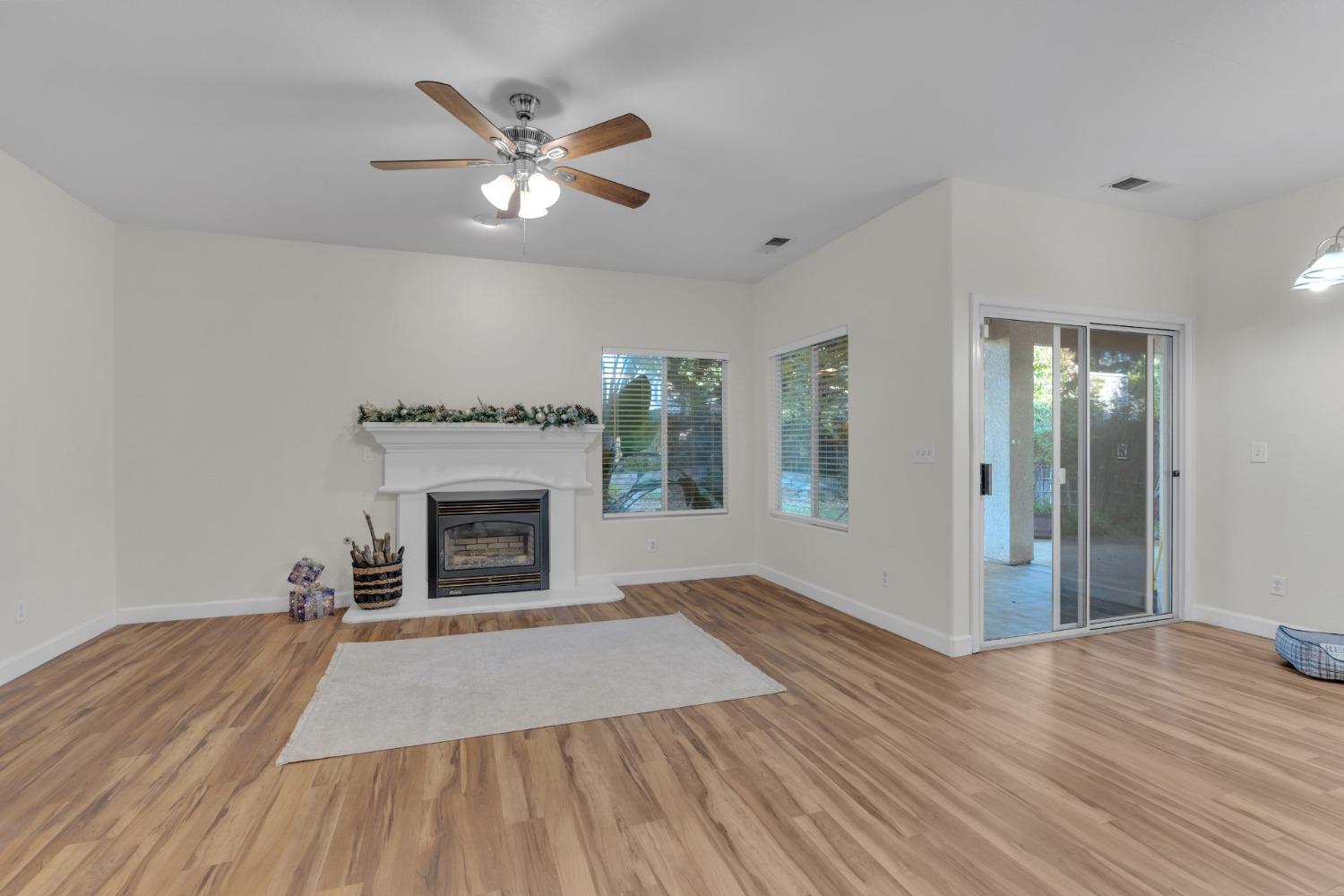 2573 Applegate Avenue Clovis, CA 93611 - Photo 19 of 26 a view of a livingroom with a fireplace a ceiling fan and wooden floor