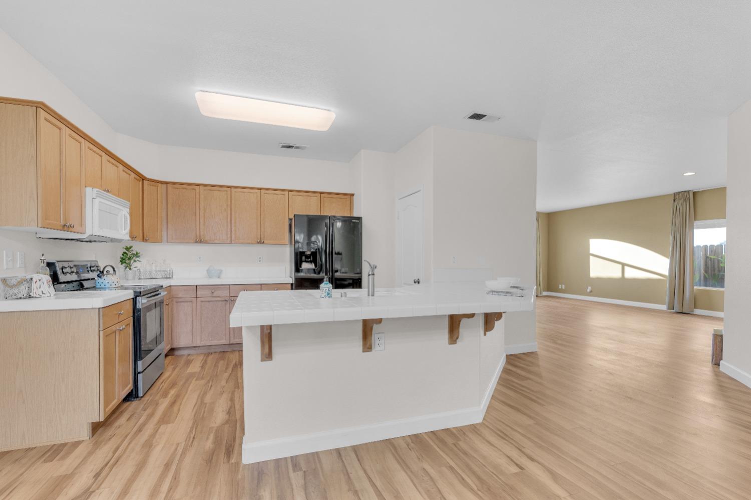 2573 Applegate Avenue Clovis, CA 93611 - Photo 9 of 26 a kitchen with stainless steel appliances a white stove top oven a sink dishwasher and white cabinets with wooden floor