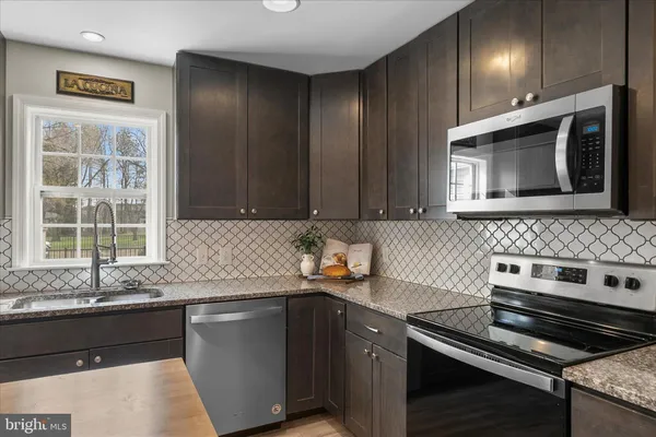 a kitchen with granite countertop cabinets stainless steel appliances and a sink
