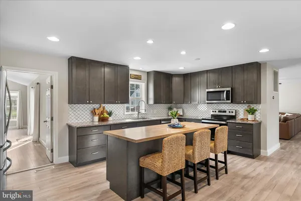a kitchen with stainless steel appliances granite countertop a stove top oven a sink dishwasher a dining table and chairs with wooden floor