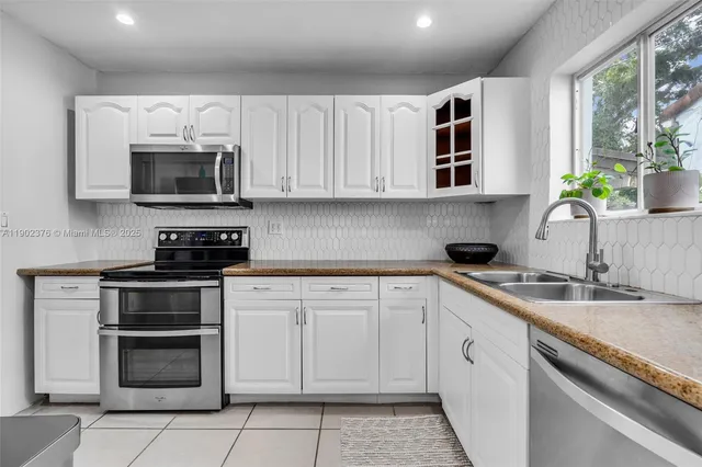 a kitchen with granite countertop white cabinets white stainless steel appliances and a sink