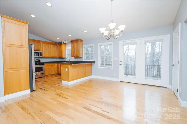 a kitchen with stainless steel appliances granite countertop wooden cabinets a sink a stove a refrigerator with grey cabinets and wooden floor