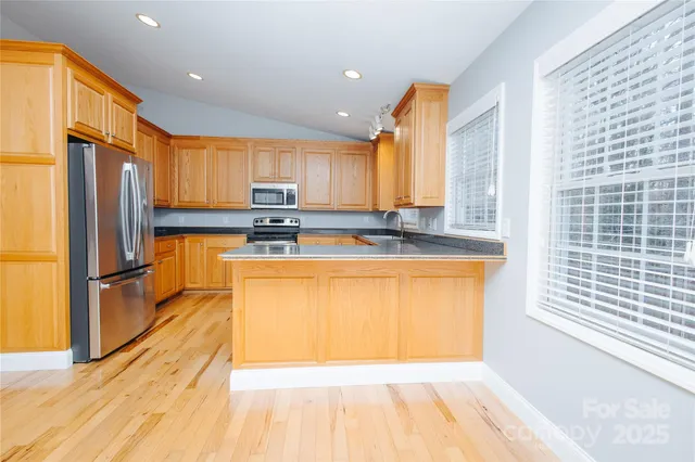 a kitchen with granite countertop wooden cabinets stainless steel appliances and a sink