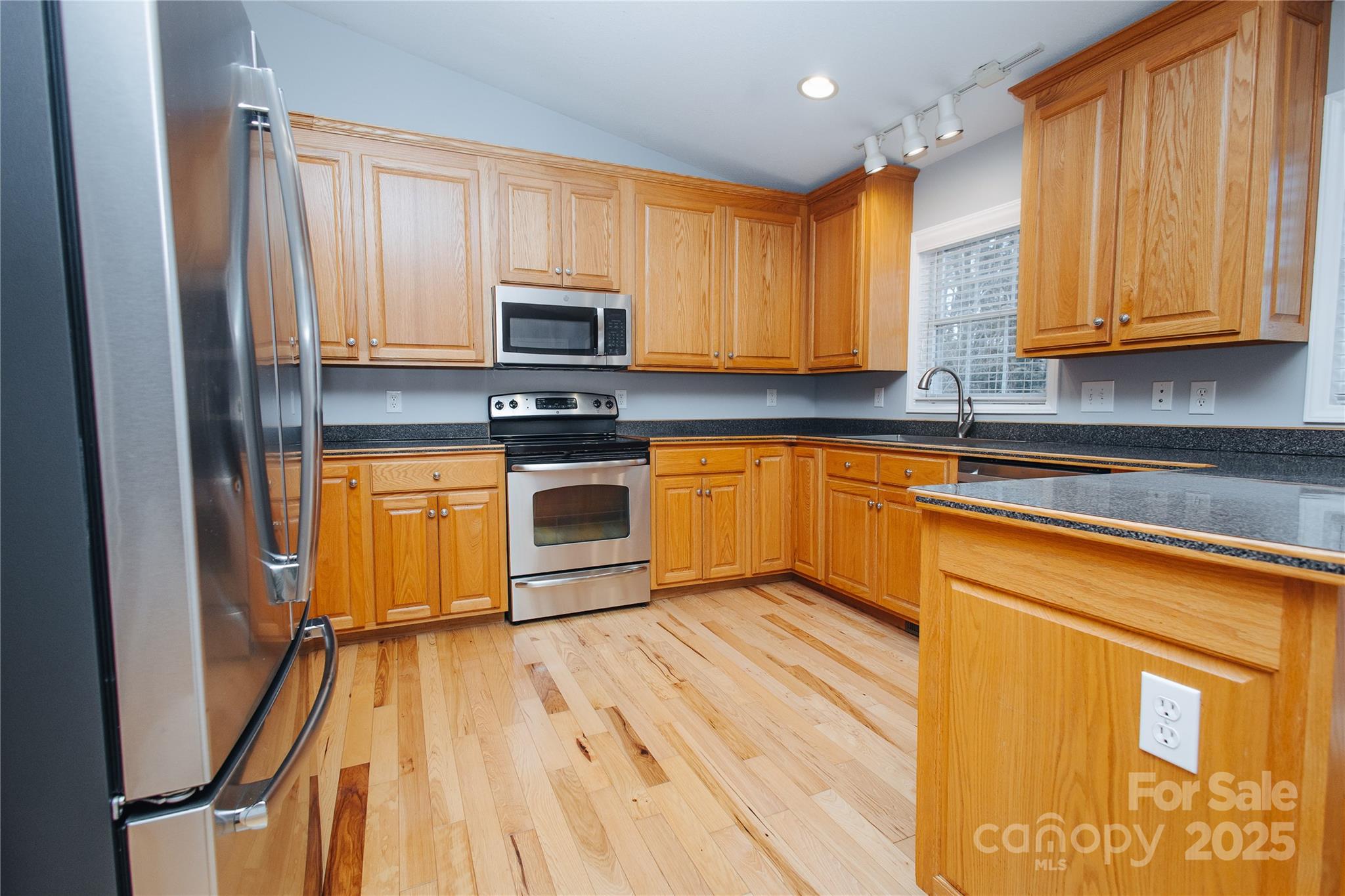 89 Bobcat Path Marion, NC 28752 - Photo 19 of 48 a kitchen with stainless steel appliances granite countertop wooden cabinets a sink a stove a refrigerator with grey cabinets and wooden floor