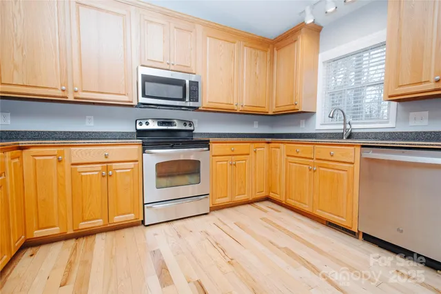 a kitchen with stainless steel appliances granite countertop a refrigerator a stove top oven and a sink with granite countertops