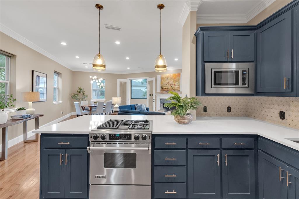 5102 Ridgedale Avenue Dallas, TX 75206 - Photo 10 of 27 Kitchen featuring a stainless steel range with a gas cooktop, white countertops, dark blue cabinetry with brushed nickel hardware, a built-in microwave, and a textured tile backsplash