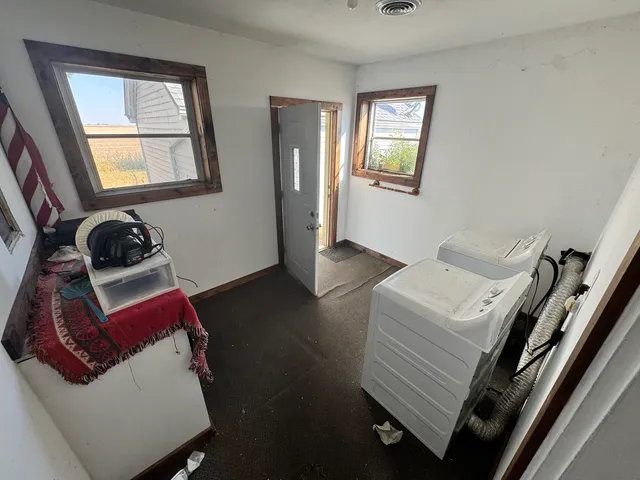 an empty room with wooden floor cabinet and windows