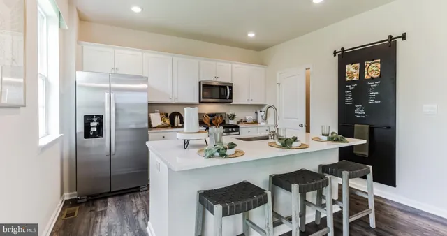 a kitchen with stainless steel appliances a refrigerator a sink a stove a table and chairs