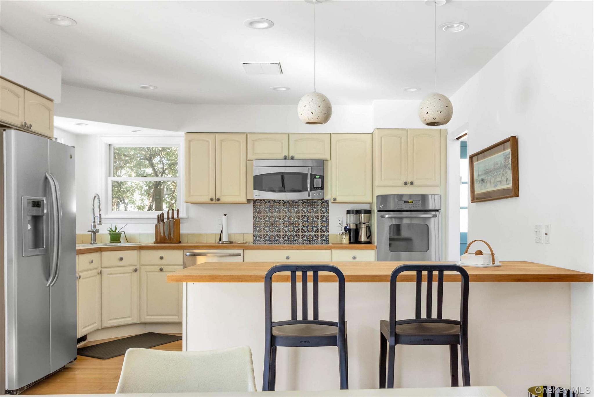 485 Pine Road Southold, NY 11971 - Photo 7 of 39 a kitchen with stainless steel appliances granite countertop a stove a sink refrigerator and white cabinets with wooden floor