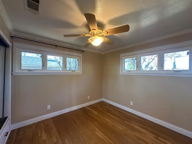 a view of an empty room with window and chandelier fan