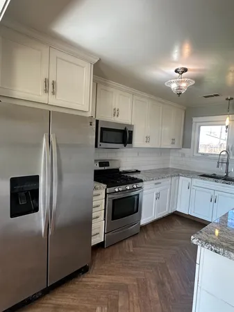 a kitchen with granite countertop a refrigerator stove top oven and sink