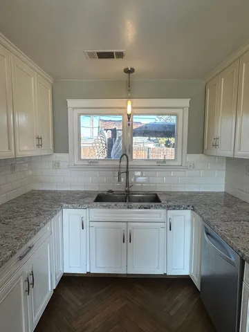 a kitchen with stainless steel appliances granite countertop a sink and dishwasher a stove top oven with wooden floor