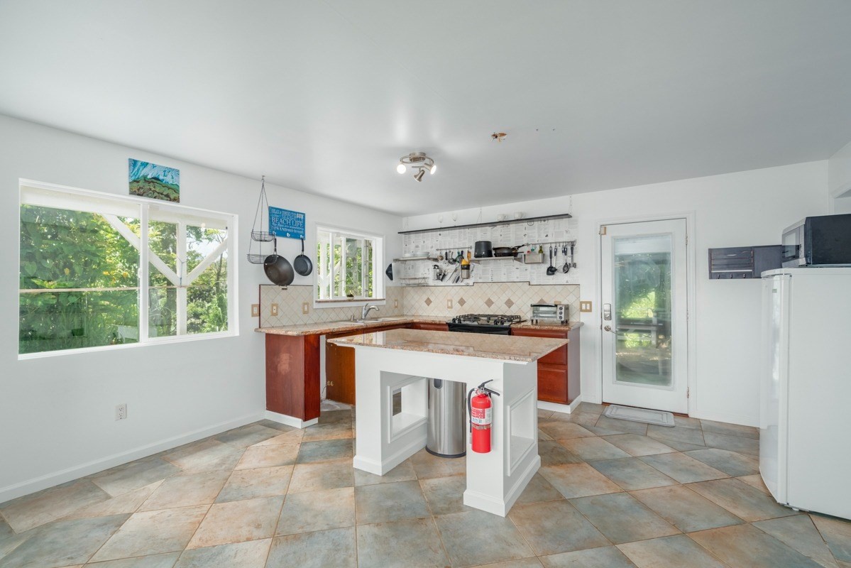 27-571 Kalaoa Camp Road Papaikou, HI 96781 - Photo 14 of 29 a kitchen with stainless steel appliances granite countertop a stove and a refrigerator