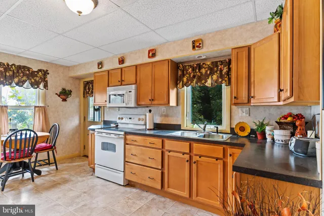 a kitchen with stainless steel appliances granite countertop sink window and white cabinets