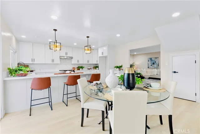 a kitchen with stainless steel appliances kitchen island granite countertop a dining table chairs and white cabinets