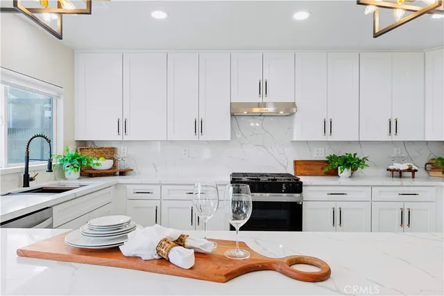 a kitchen with stainless steel appliances granite countertop a sink and white cabinets