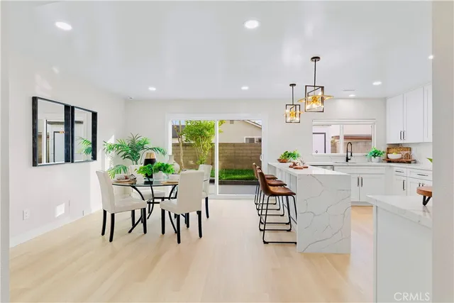 a kitchen with stainless steel appliances kitchen island granite countertop a table chairs and a refrigerator