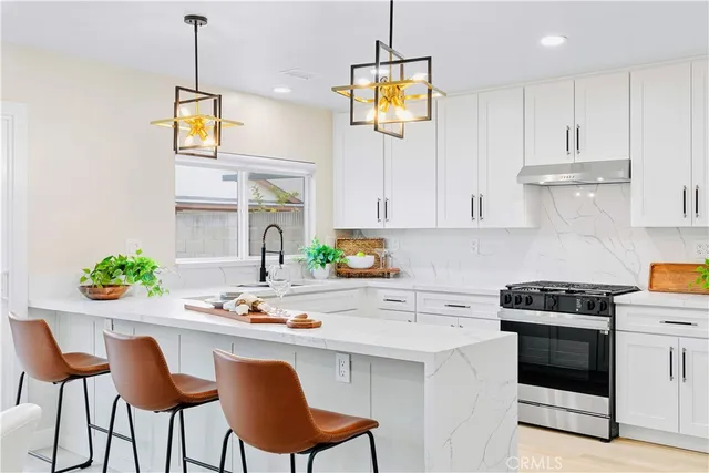 a kitchen with stainless steel appliances a white table chairs and a refrigerator
