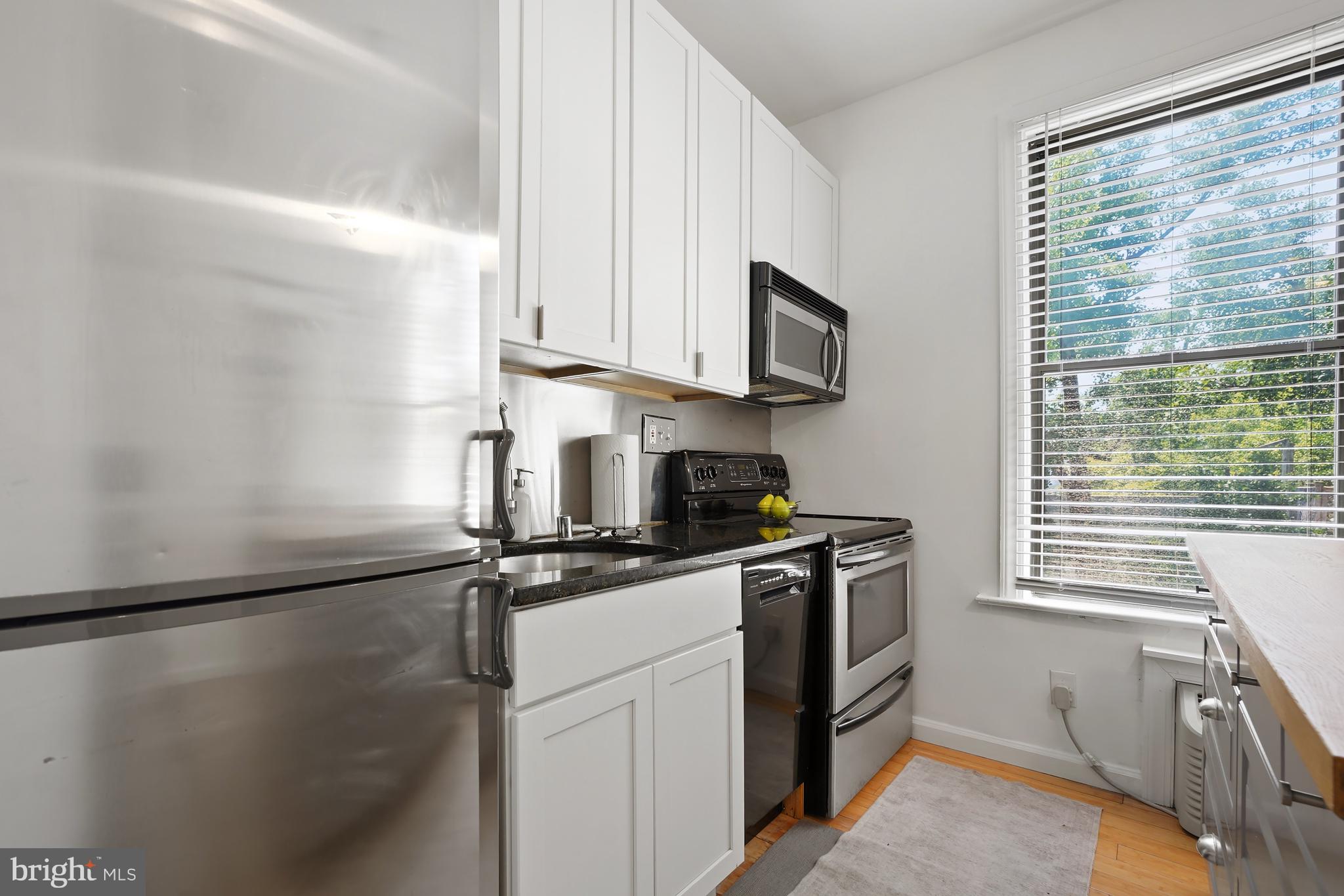 1822 15th Street Northwest, Unit 303 Washington, DC 20009 - Photo 5 of 22 a kitchen with stainless steel appliances granite countertop a sink stove and refrigerator
