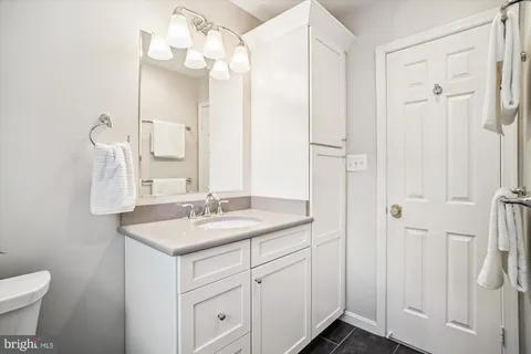 a bathroom with a granite countertop sink mirror and a toilet