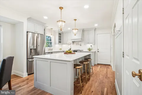 a kitchen that has a lot of white cabinets and stainless steel appliances