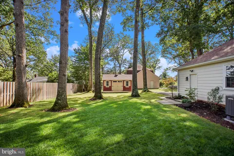 a view of a white house next to a yard with big trees