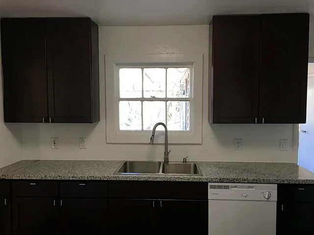 a kitchen with granite countertop stainless steel appliances a sink stove and cabinets