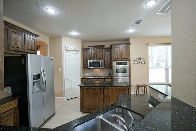 a kitchen with stainless steel appliances granite countertop a refrigerator and a stove top oven