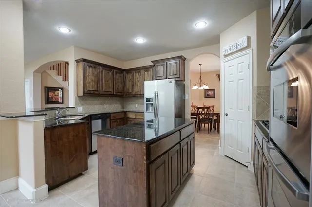 a kitchen with stainless steel appliances granite countertop a refrigerator a stove a sink and dishwasher