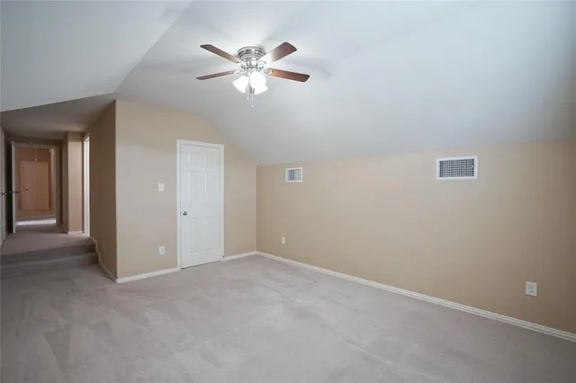 a view of an empty room with chandelier fan