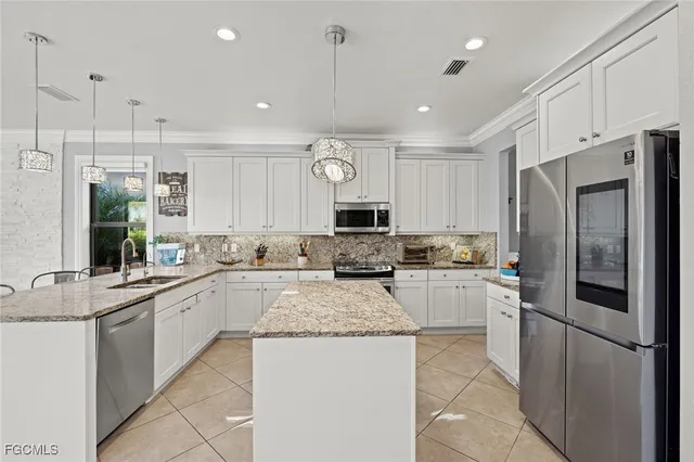 a large kitchen with a refrigerator a stove a sink a center island a stove and cabinets