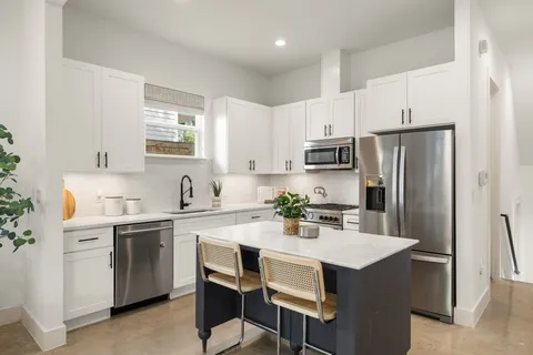 a kitchen with a sink a refrigerator and white cabinets