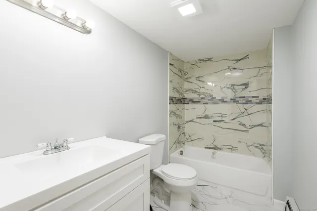 a bathroom with a granite countertop sink a toilet and shower