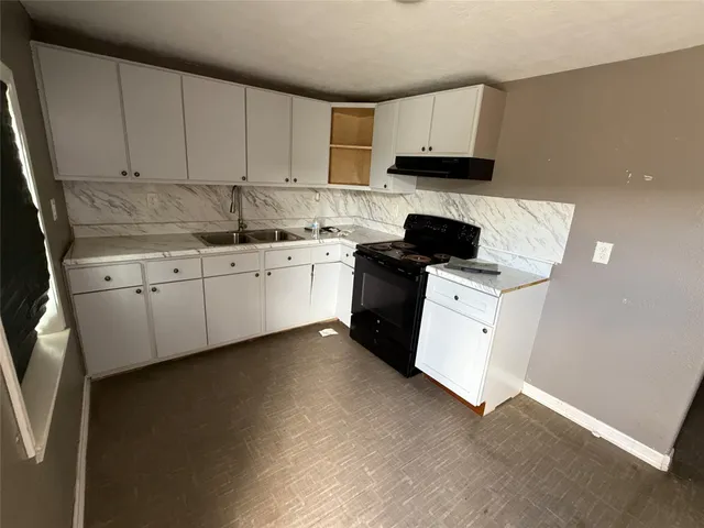 a kitchen with granite countertop white cabinets sink and stainless steel appliances