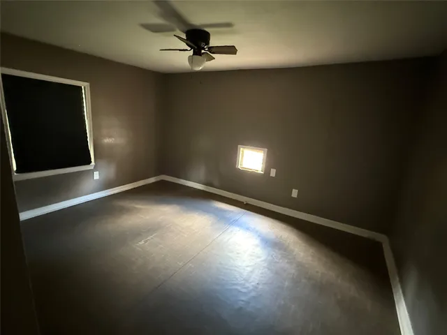 an empty room with a window and a ceiling fan