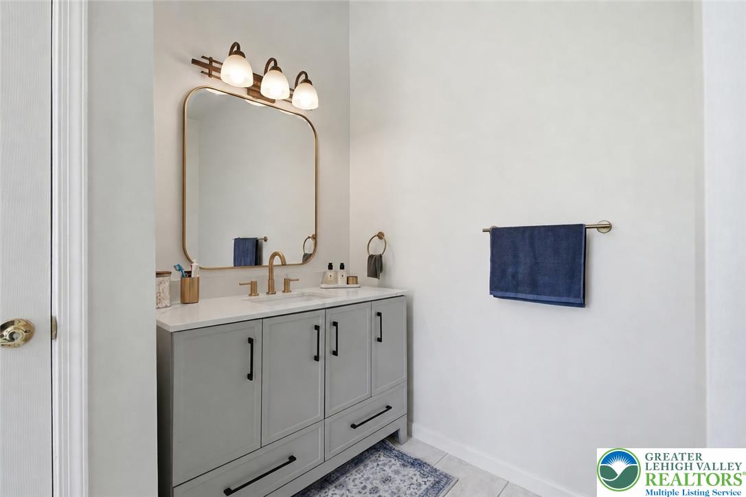 115 West Butternut Road Hellertown, PA 18055 - Photo 43 of 97 A sleek vanity with ample storage and a gold-framed mirror anchors this well-appointed bathroom.