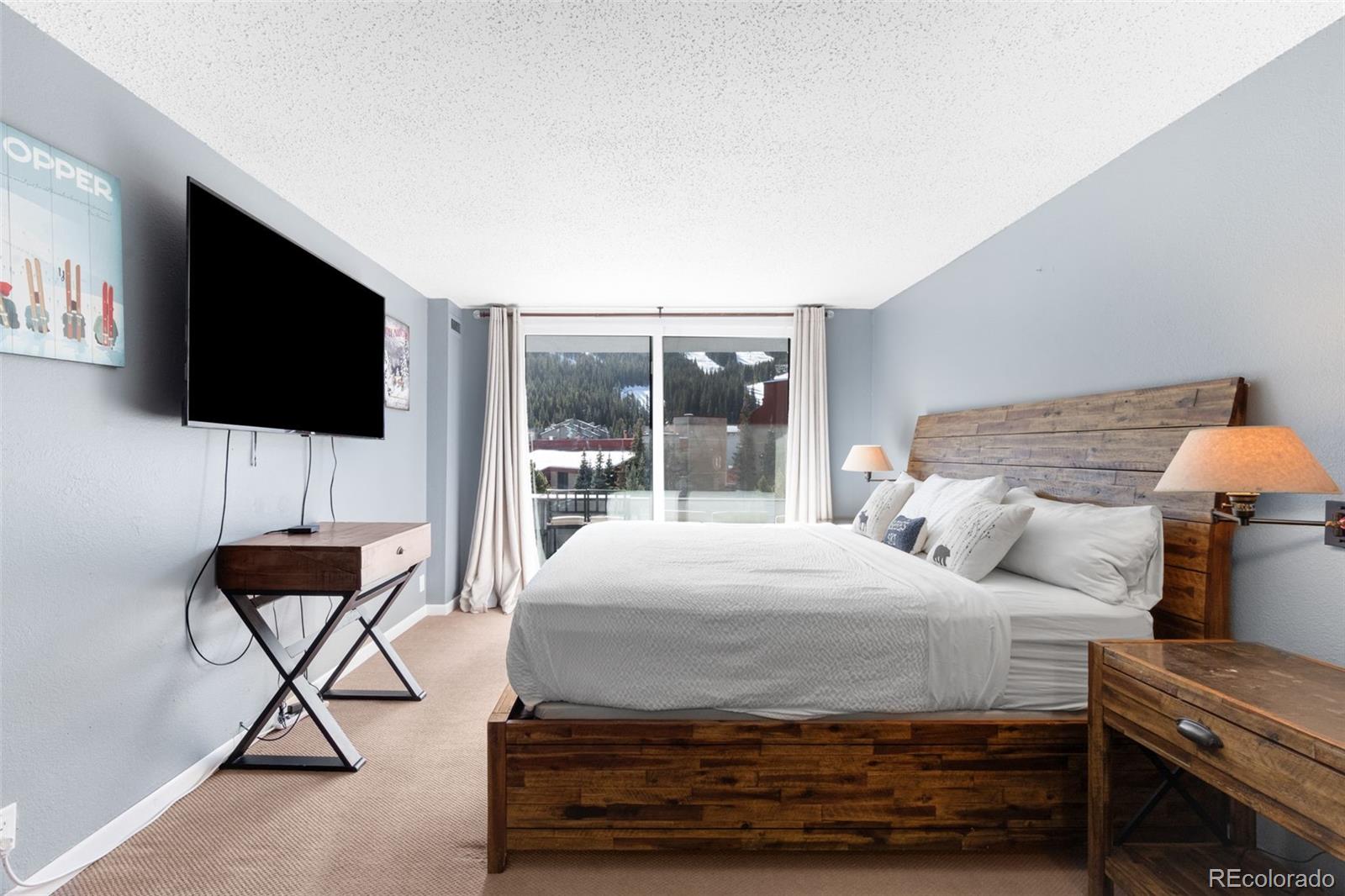 760 Copper Road, Unit F204 Frisco, CO 80443 - Photo 14 of 30 a bedroom with a bed and a flat screen tv