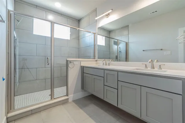 a bathroom with a double vanity sink mirror and shower
