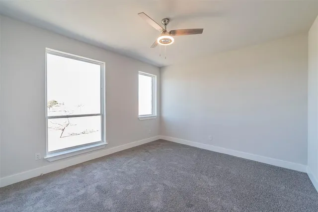 an empty room with windows and fan