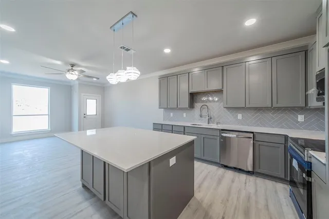 a kitchen that has a sink a microwave oven a stove and white cabinets with wooden floor