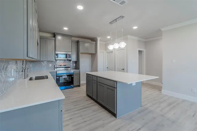 a kitchen with kitchen island a sink a stove a refrigerator and a oven