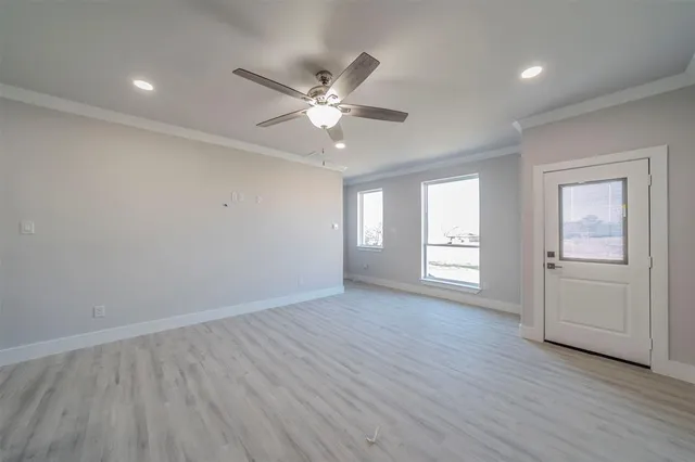 an empty room with wooden floor closet and windows