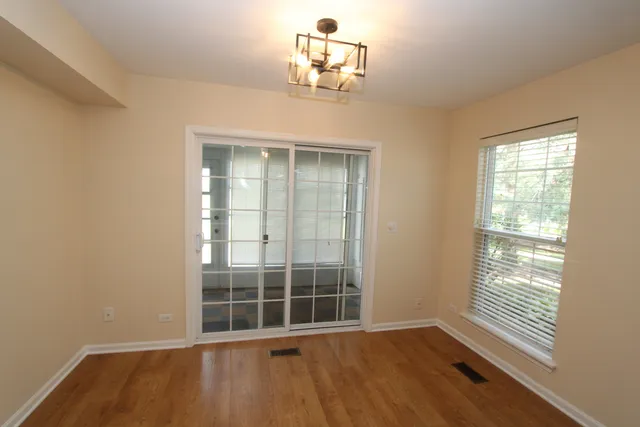 an empty room with wooden floor cabinet and windows