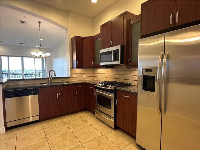a large kitchen with stainless steel appliances granite countertop a refrigerator and a stove