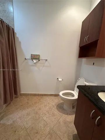 a bathroom with a granite countertop toilet and a sink