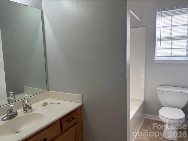 a bathroom with a granite countertop toilet sink and mirror