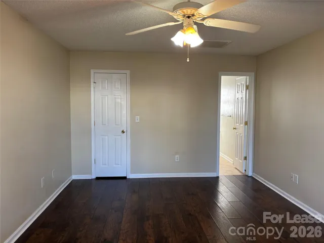 an empty room with wooden floor closet and fan